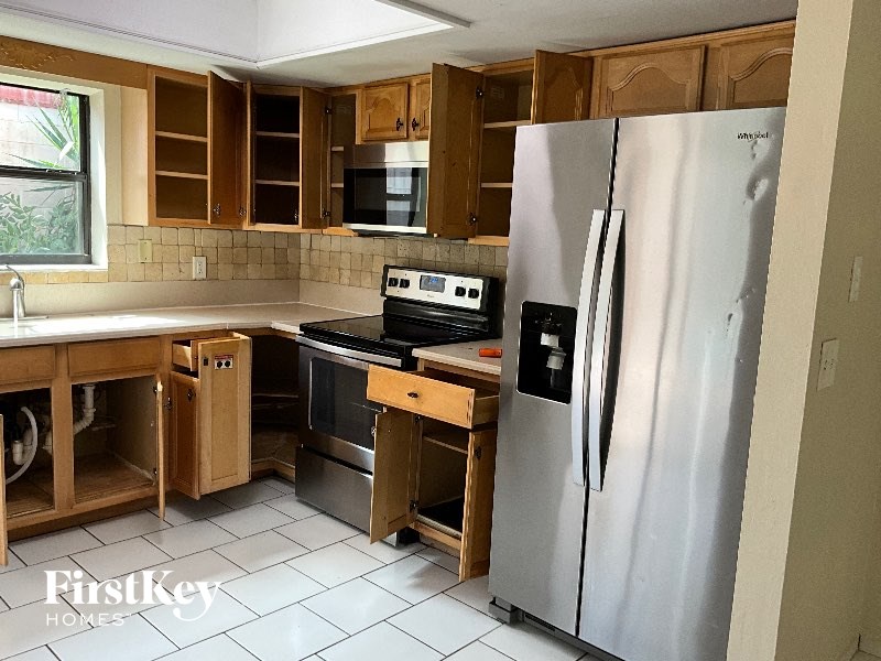 A kitchen with a stainless steel refrigerator and wooden cabinets.