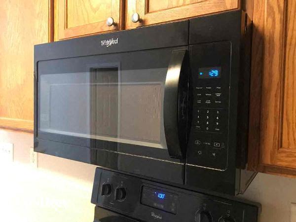 a black microwave in a kitchen with wooden cabinets
