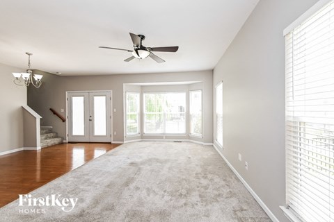 an empty living room with a ceiling fan and a carpet