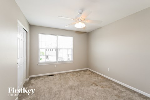 a bedroom with carpet and a ceiling fan and a window