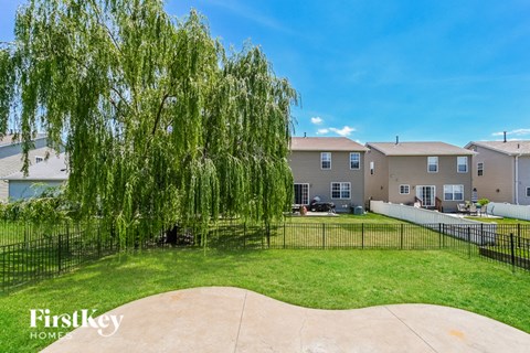 a backyard with a weeping willow tree and some apartment buildings