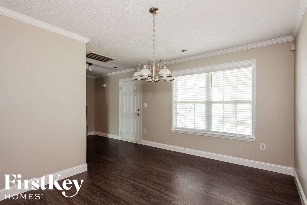 an empty dining room with a window and a chandelier