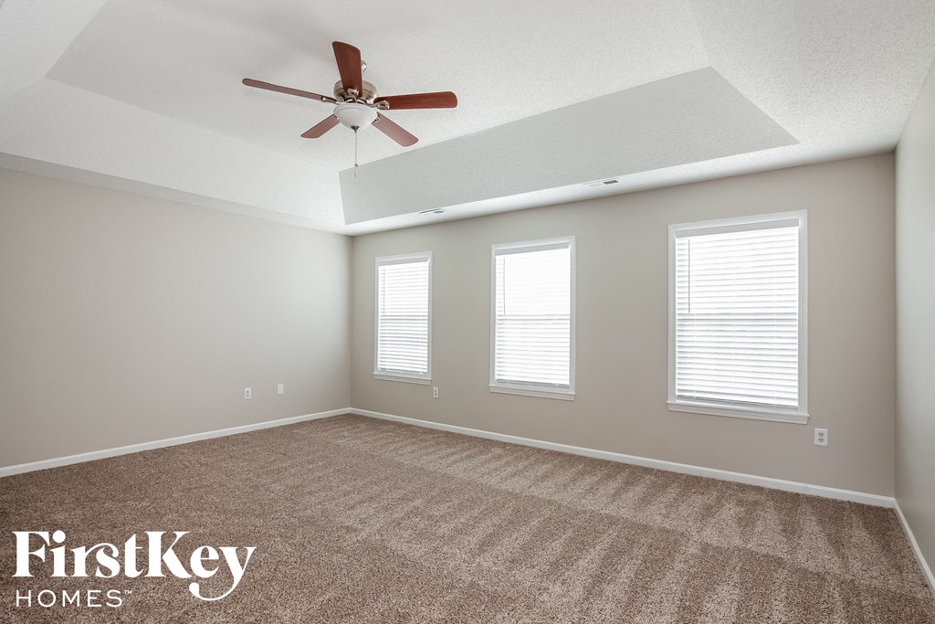 a living room with a ceiling fan and three windows