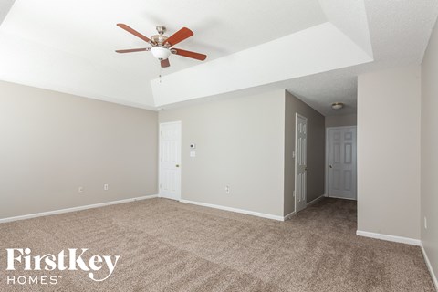 a living room with carpet and a ceiling fan