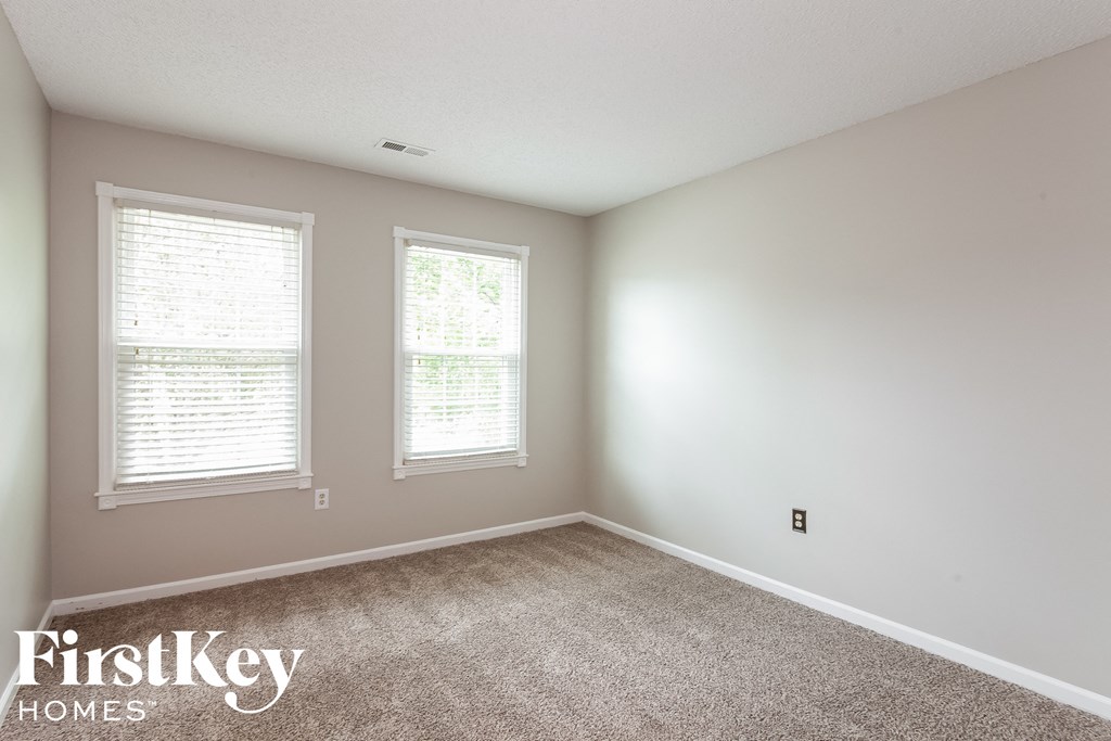 a bedroom with a carpeted floor and two windows