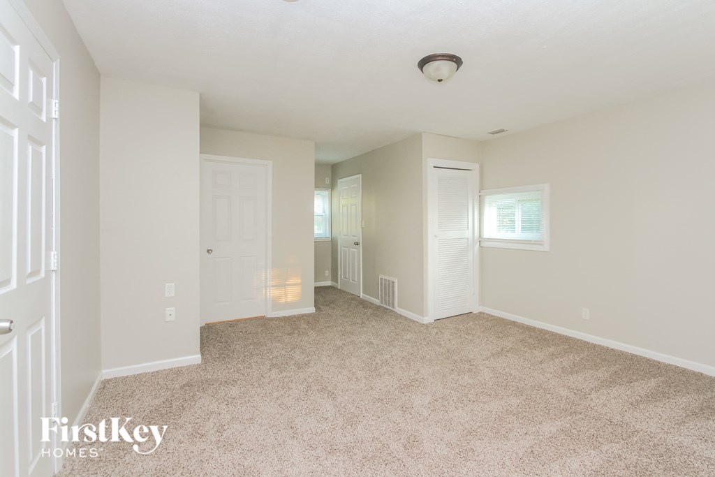 A spacious room with a carpeted floor and white walls.