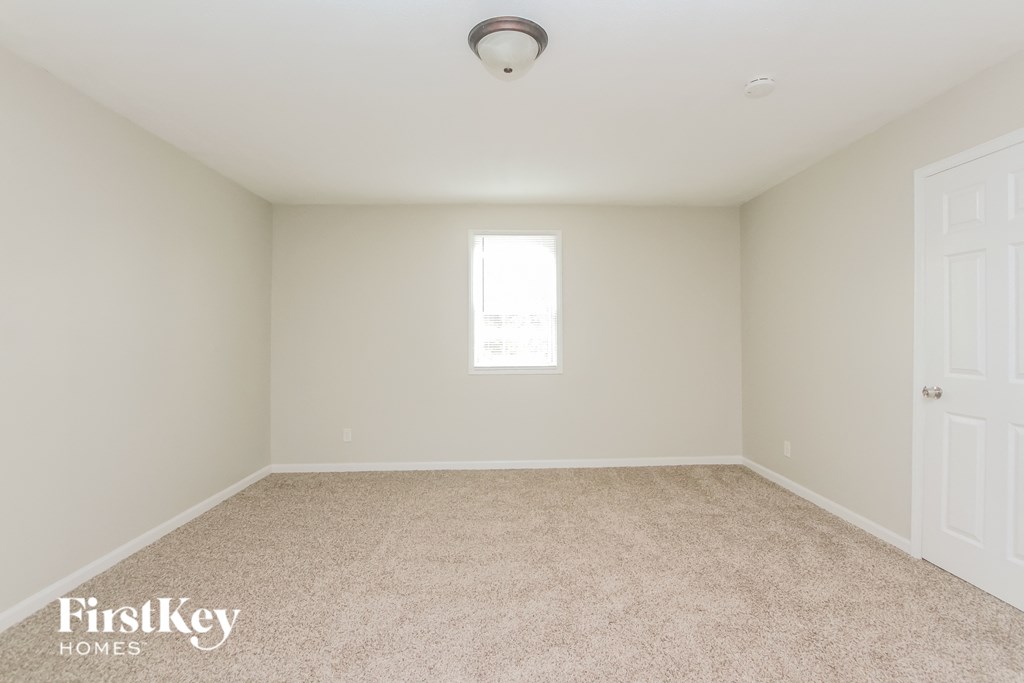 A room with a carpeted floor and a window letting in natural light.