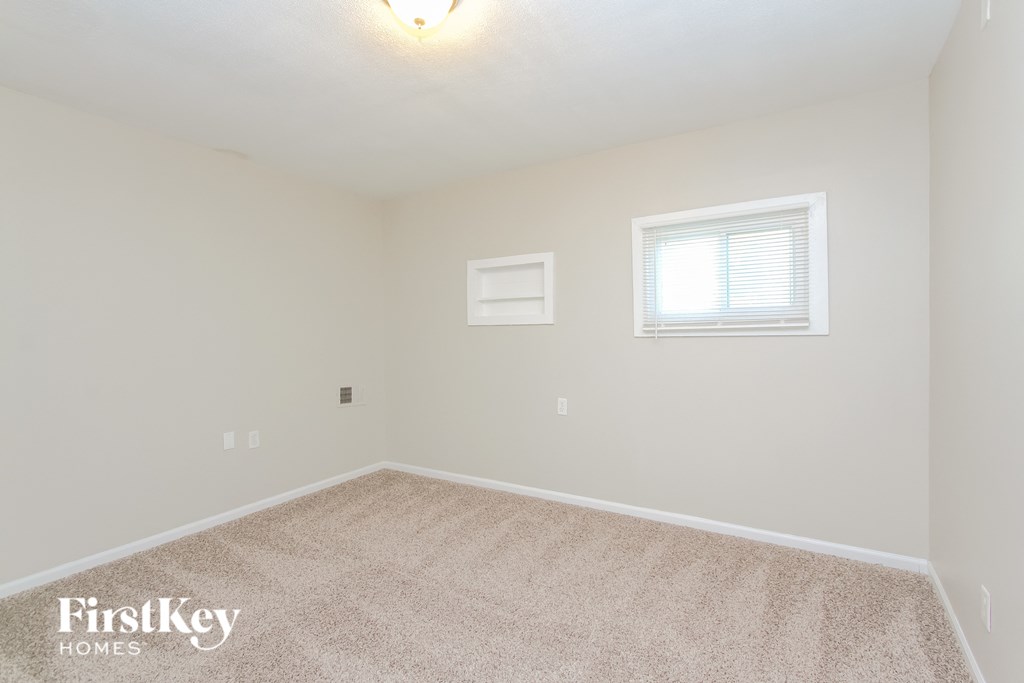 A carpeted room with a window and a light switch.