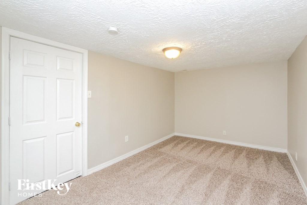 A room with a white door and carpeted floor.