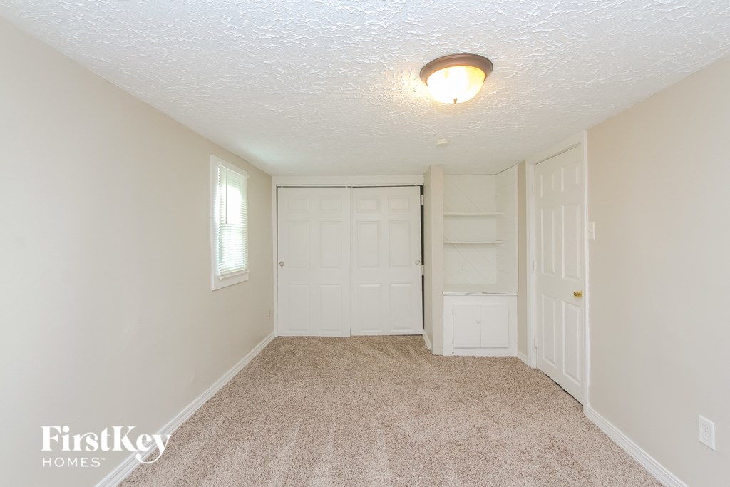 A white door is in the middle of a room with a carpet floor.