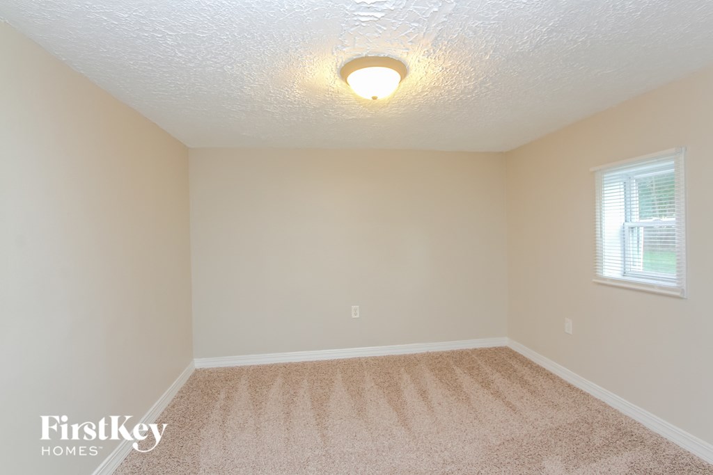 A room with a carpeted floor and a window with blinds.