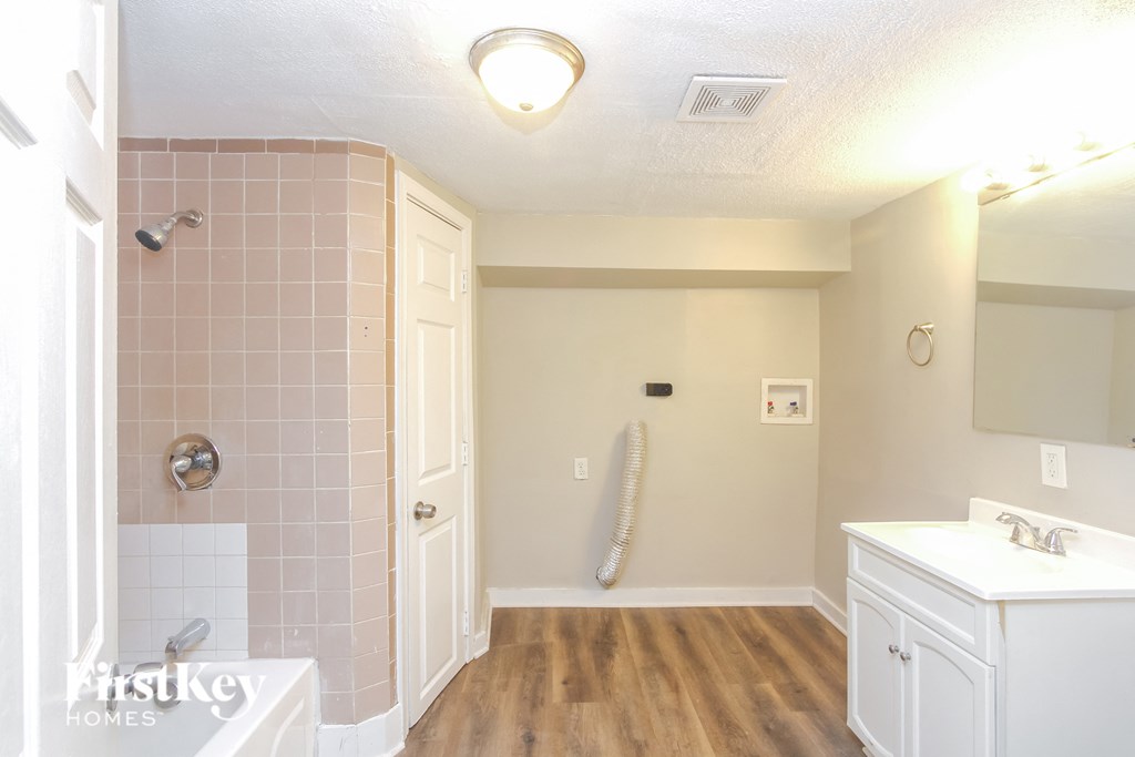 A bathroom with a white sink and a pink tiled shower.