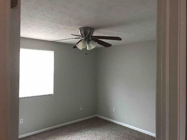 an empty room with a ceiling fan and a window