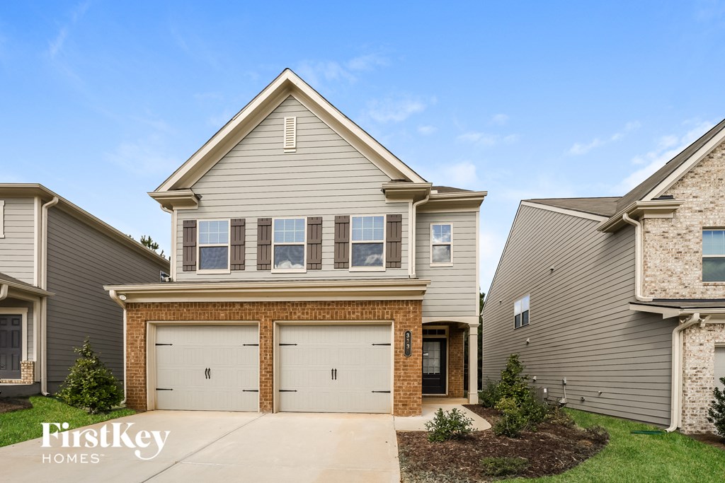 a beige and brick house with two garage doors