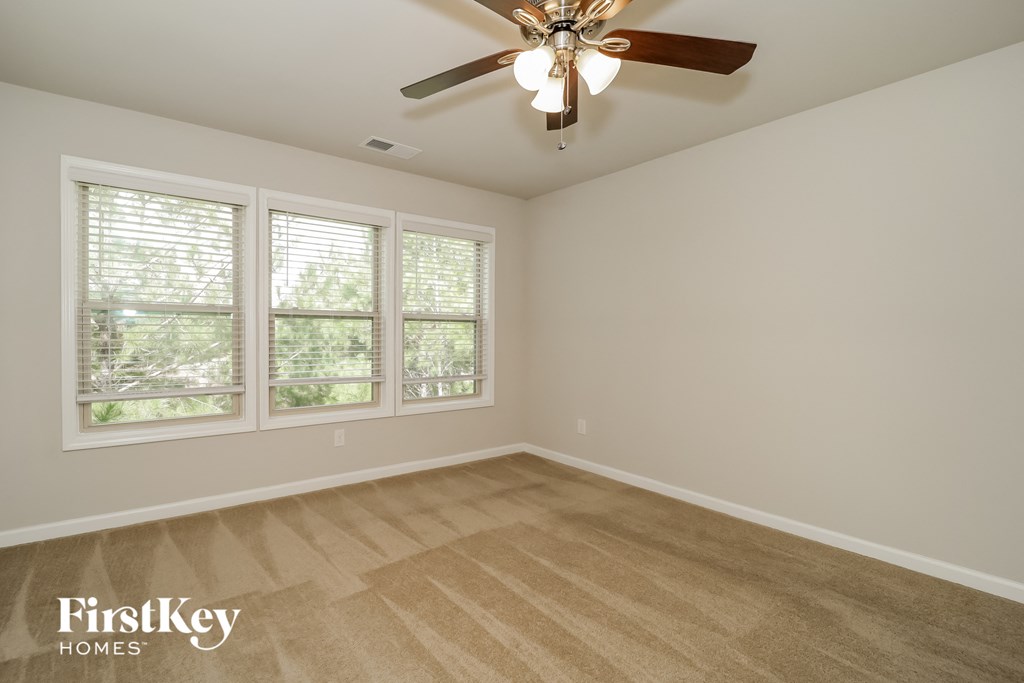 an empty living room with a ceiling fan and windows