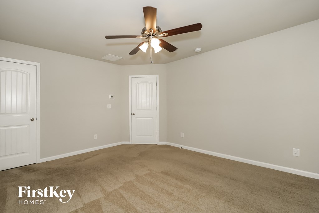 a empty living room with a ceiling fan and carpet
