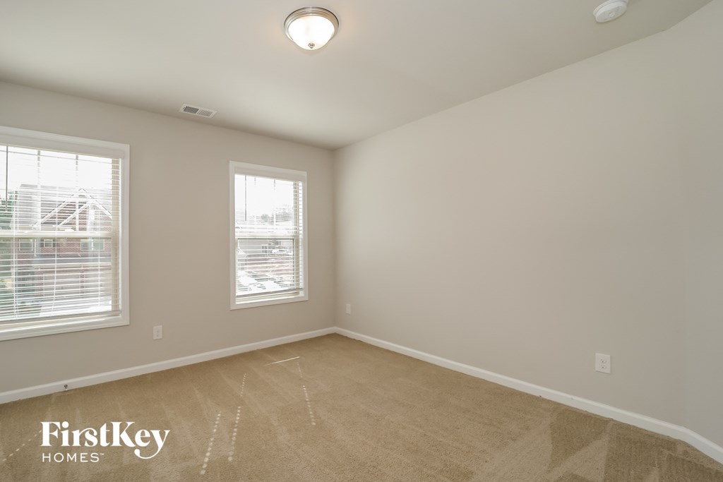 a bedroom with a carpeted floor and two windows