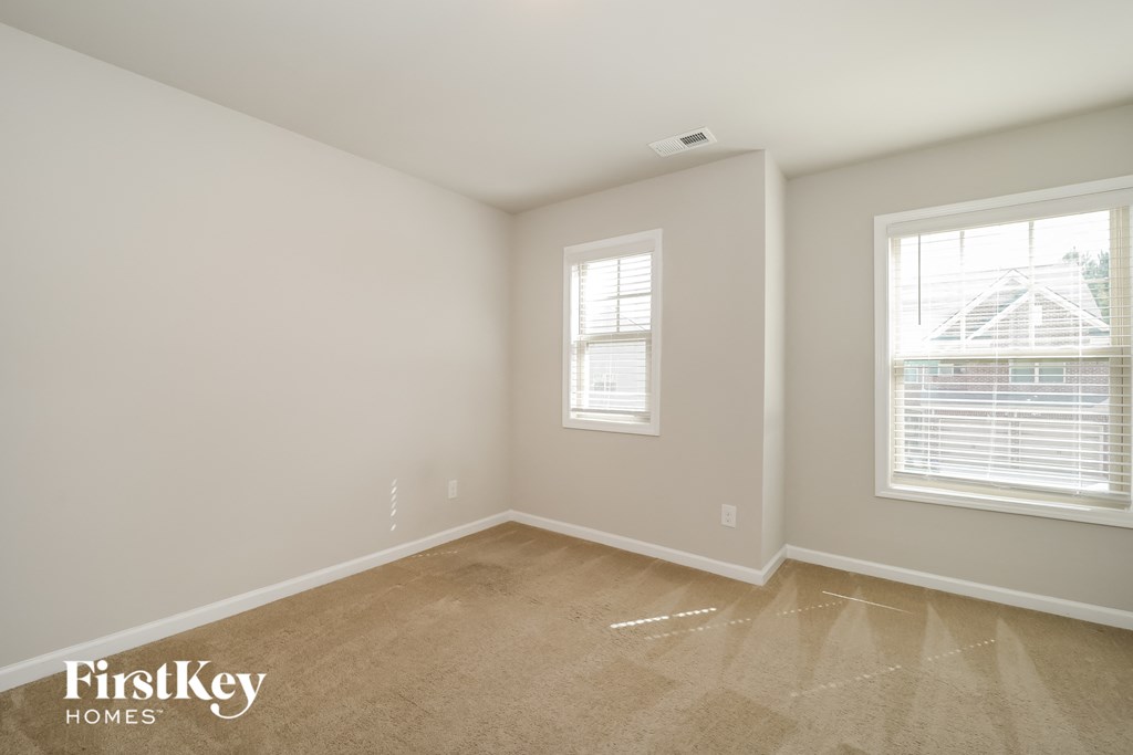 a bedroom with a carpeted floor and two windows