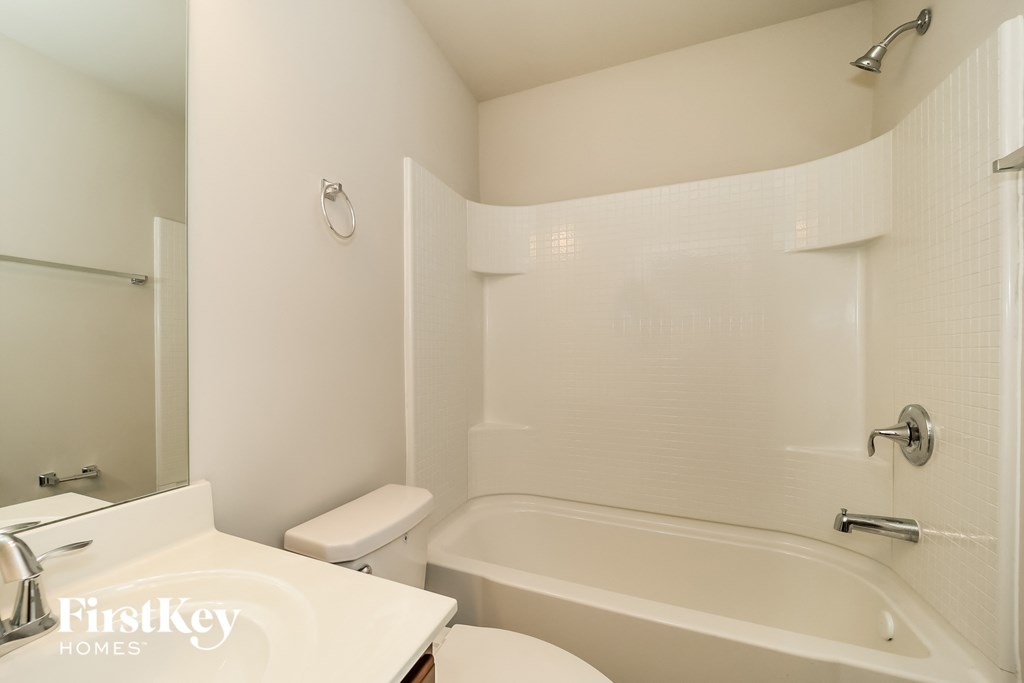 a white bathroom with a tub and a sink and a toilet