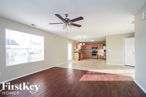 A spacious living room with a wood floor and a ceiling fan.
