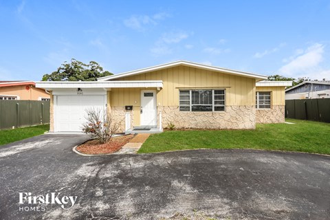 a small yellow house with a driveway and grass