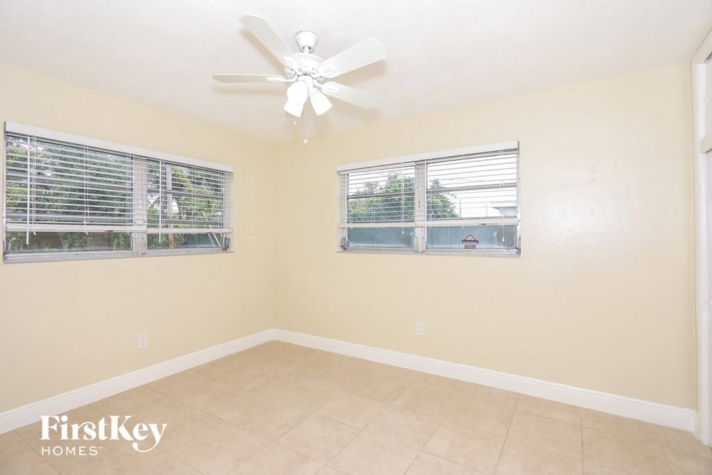 an empty room with two windows and a ceiling fan
