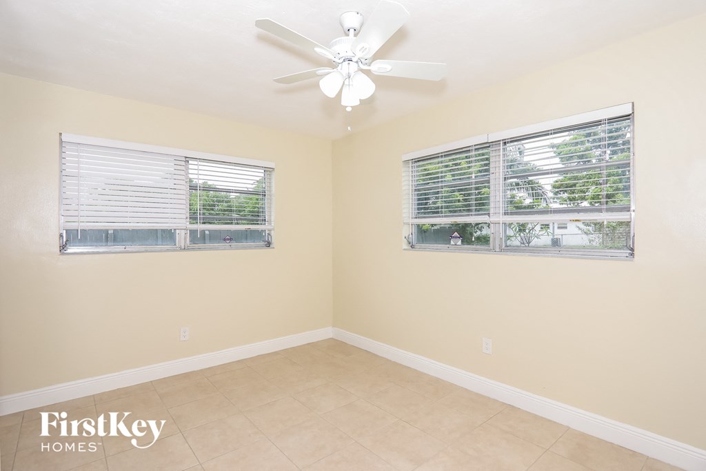 an empty living room with a ceiling fan and two windows