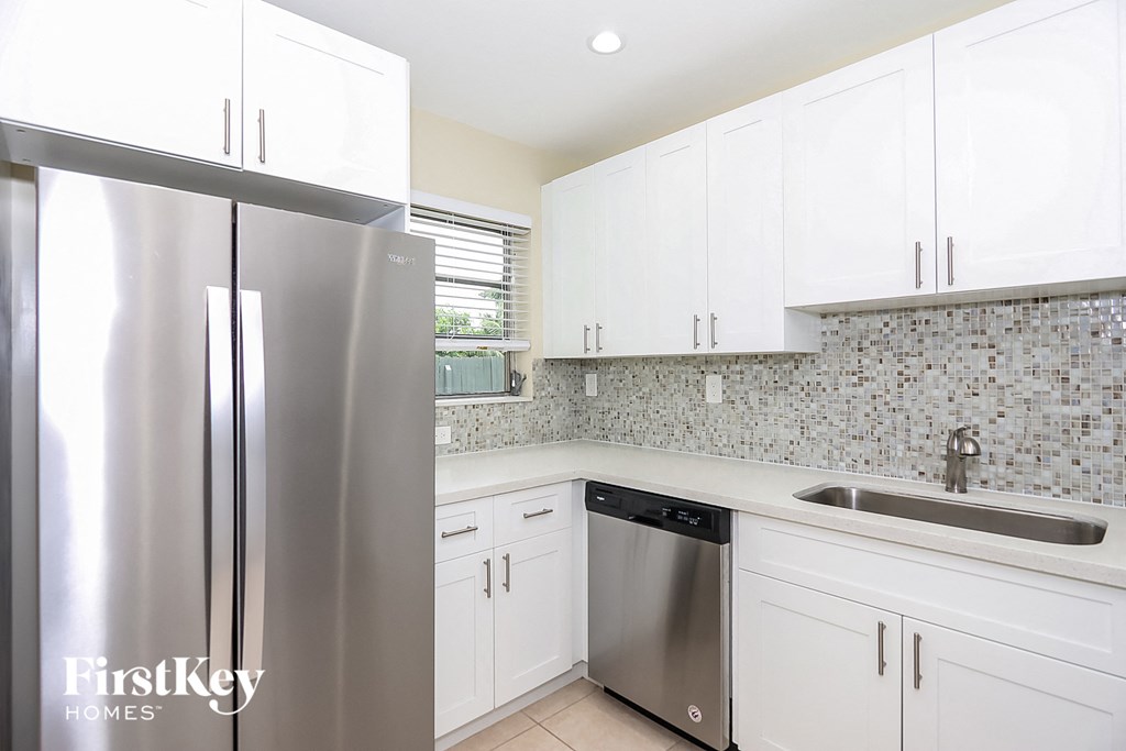 a white kitchen with stainless steel appliances and white cabinets