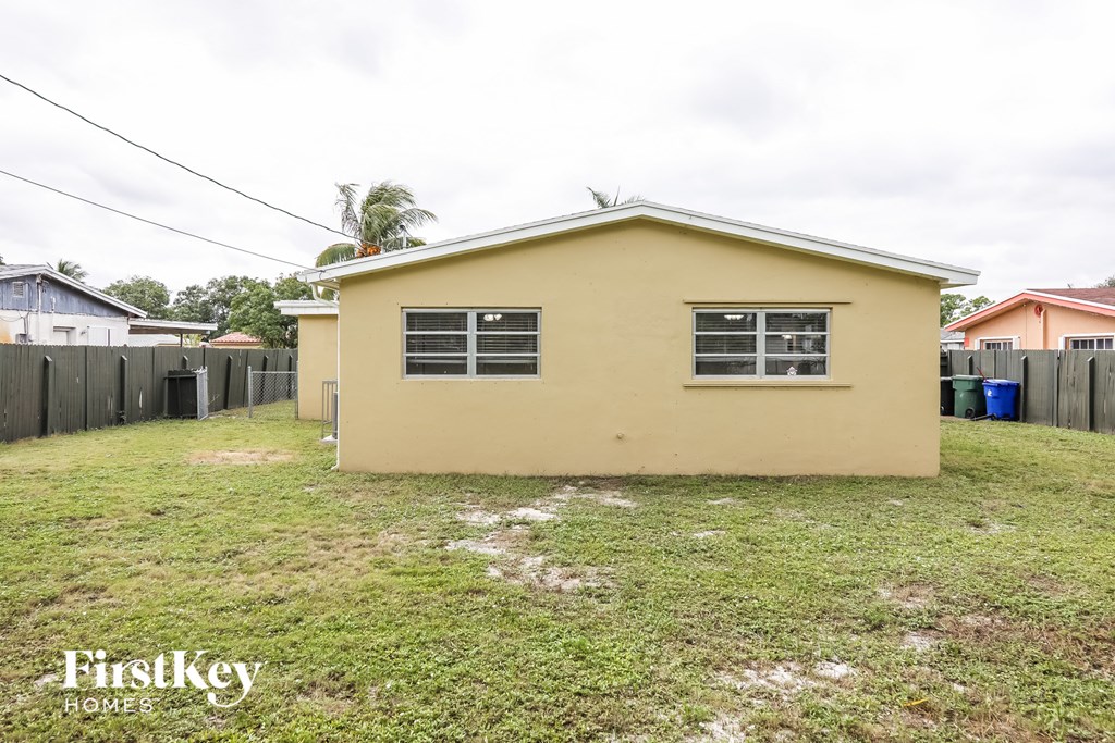 a small yellow house with a yard and a fence