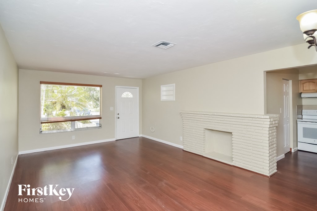 an empty living room with wood flooring and a fireplace