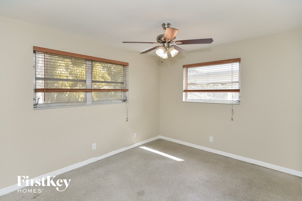 a living room with a ceiling fan and two windows