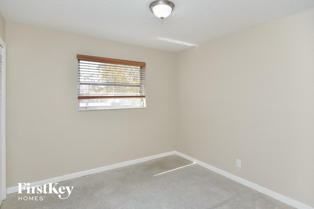 a bedroom with a window and a carpeted floor