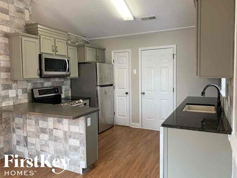 A kitchen with a stone backsplash and wooden floors.