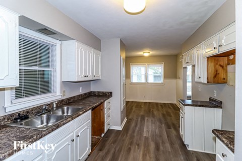 A kitchen with white cabinets and a granite countertop.