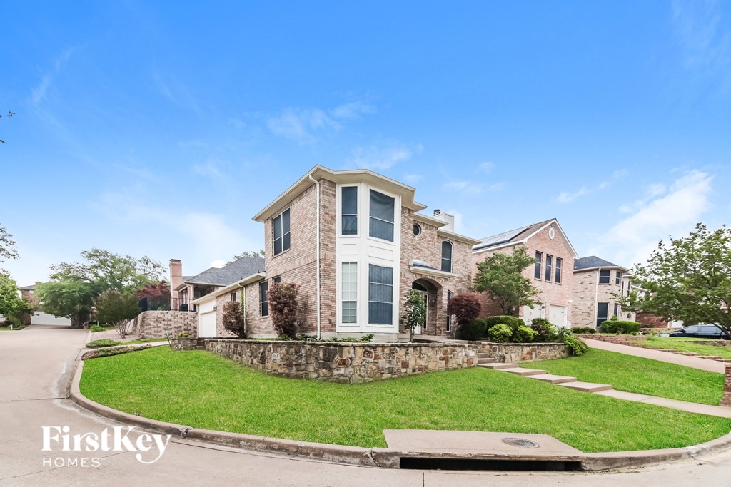 A house with a stone wall and a grassy front yard.