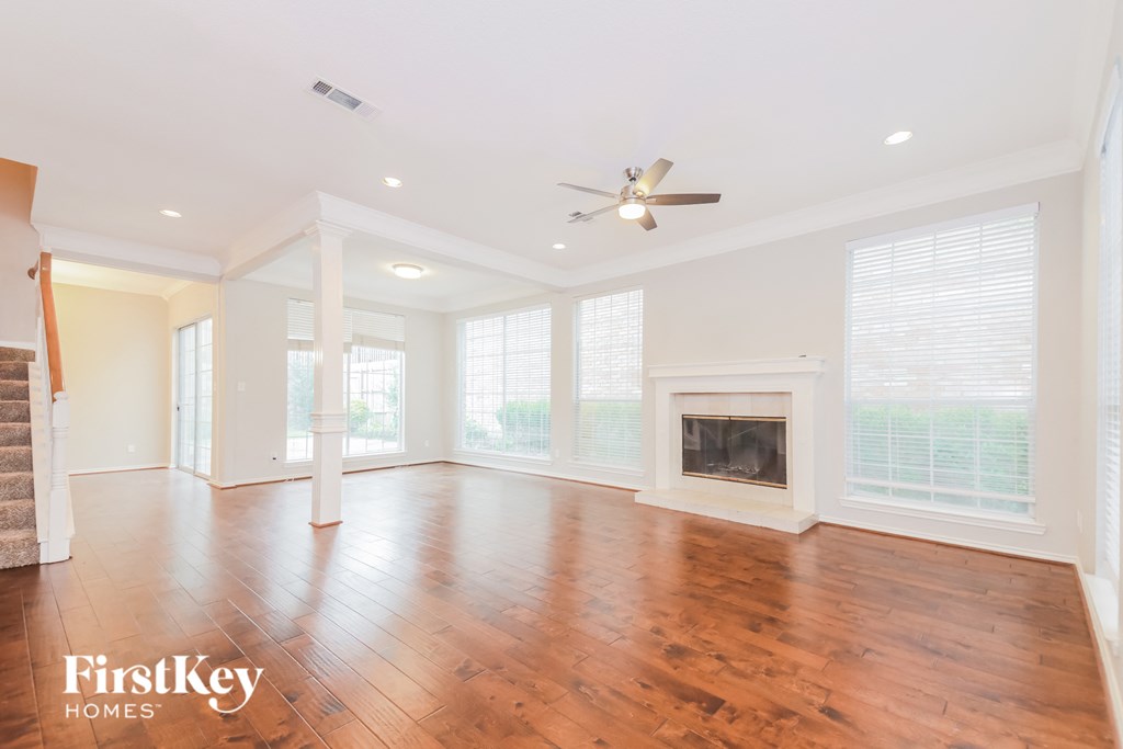 A spacious living room with wood flooring and a fireplace.