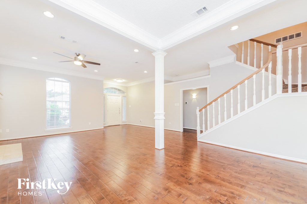 A spacious room with wooden floors and a staircase.