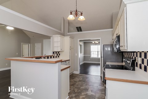 A kitchen with a checkered backsplash and a refrigerator.