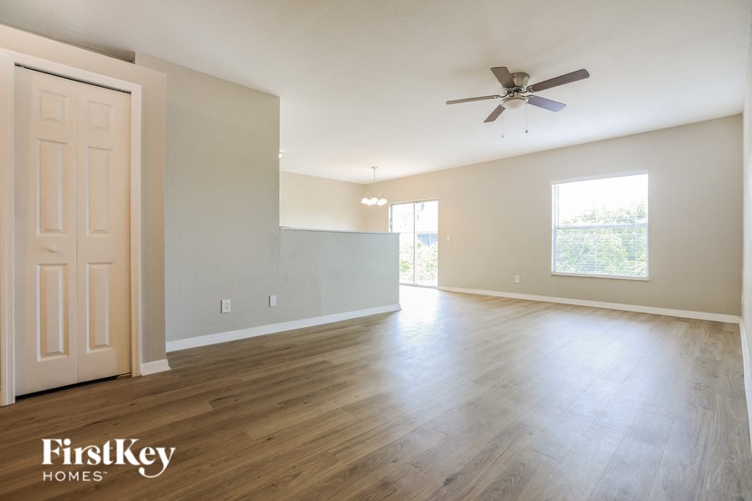 A spacious room with a wooden floor and a ceiling fan.