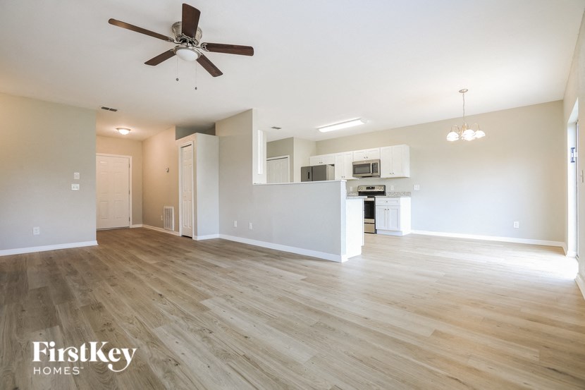 A spacious room with a fan and wooden flooring.