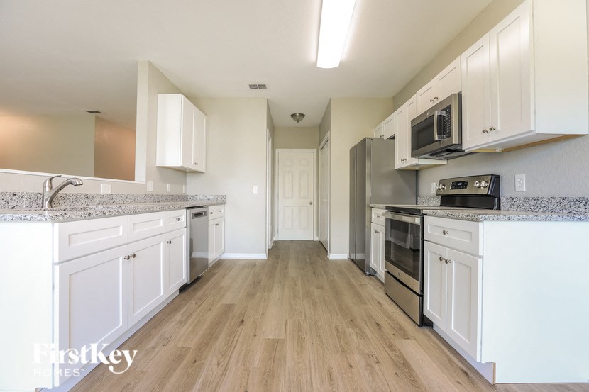 A kitchen with white cabinets and a wooden floor.