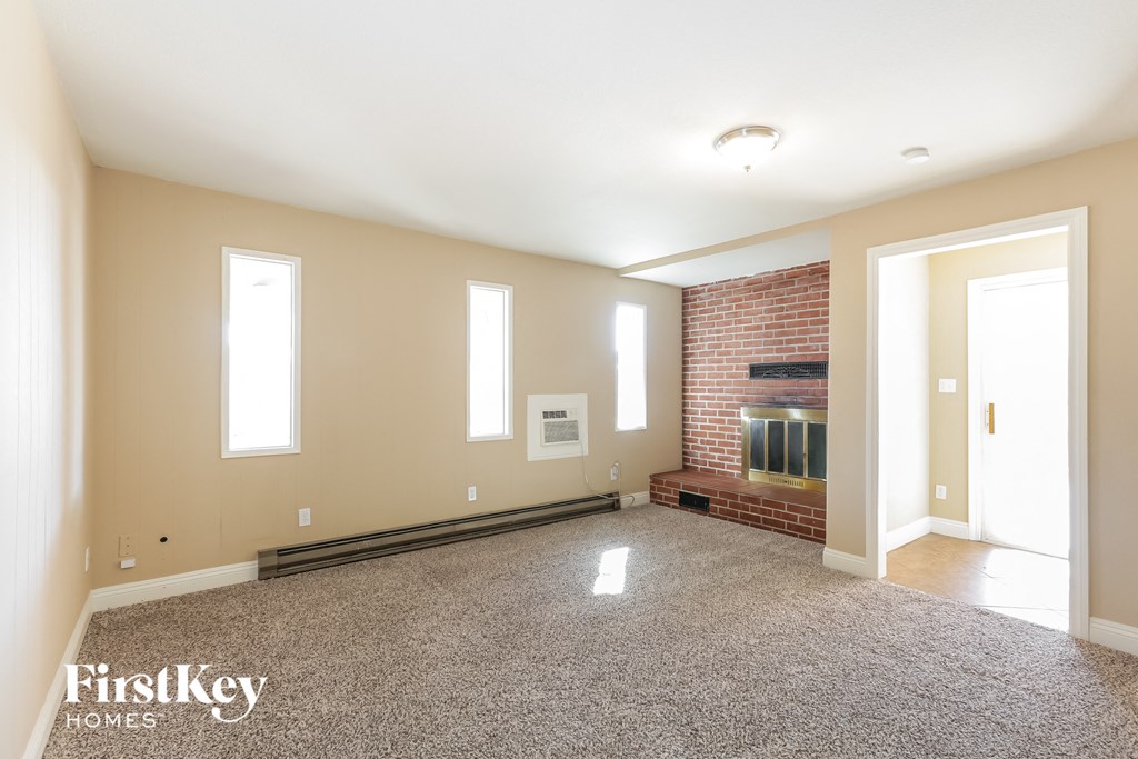 a empty living room with a brick fireplace and a carpeted floor