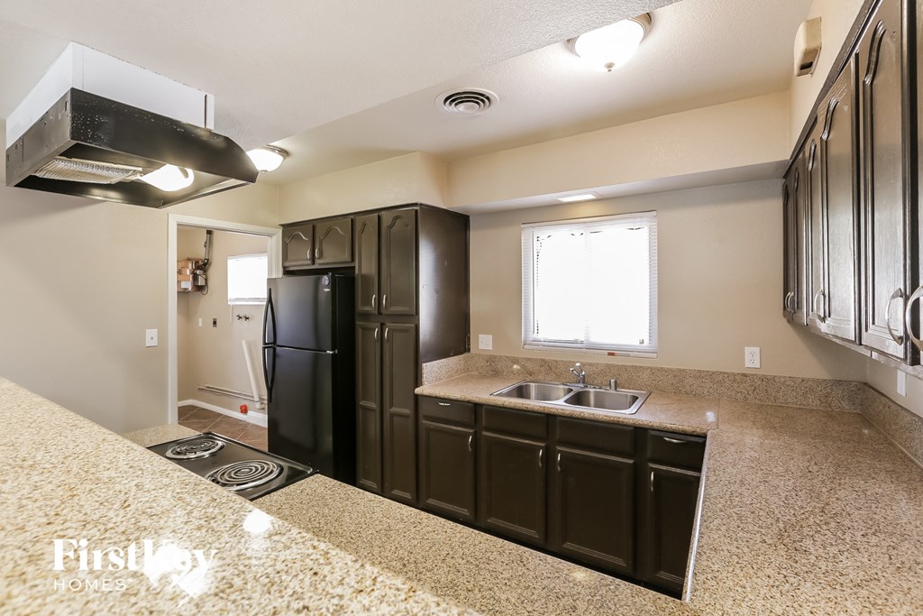 an empty kitchen with black appliances and granite counter tops