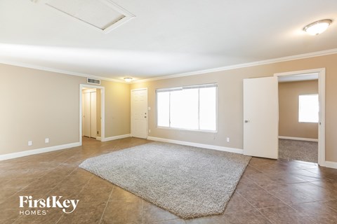 a spacious living room with tile flooring and a rug
