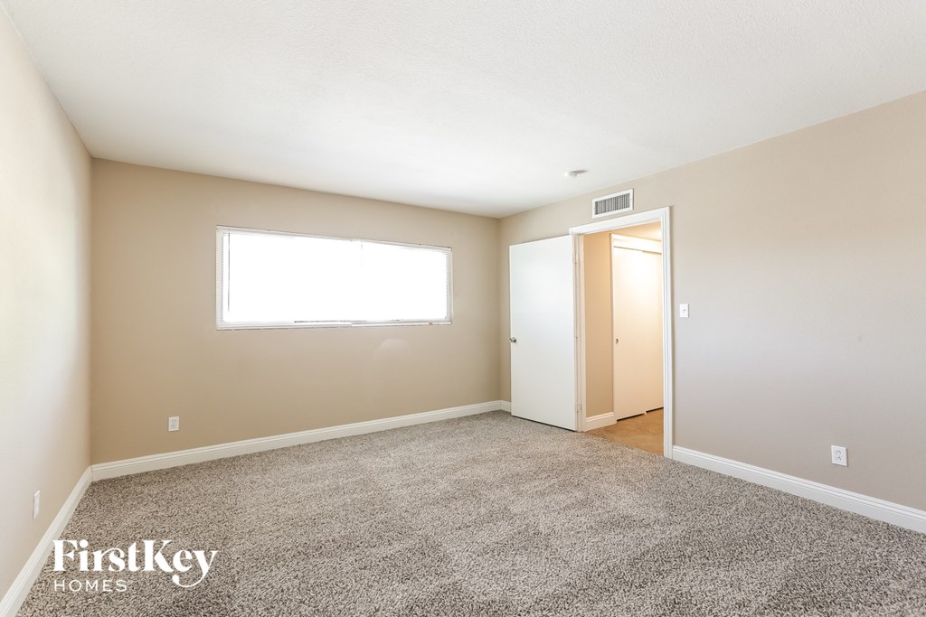 a spacious living room with carpet and a door to a bedroom