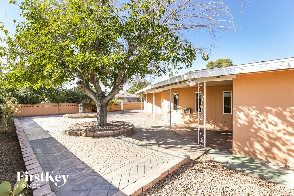 a tree in the middle of a brick driveway in front of a house