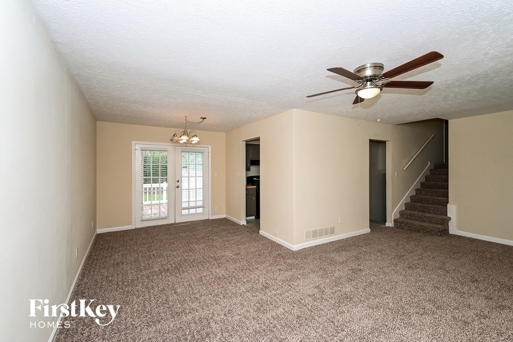 an empty living room with a ceiling fan and a staircase