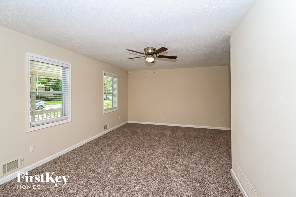 an empty living room with a ceiling fan and a window