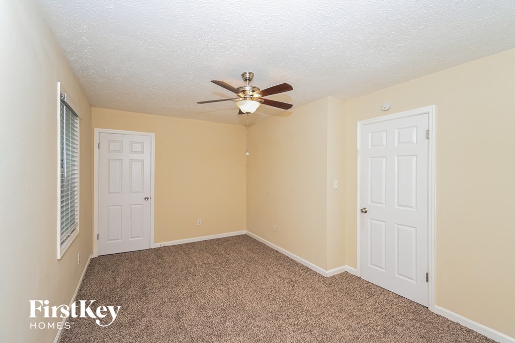 a bedroom with two doors and a ceiling fan