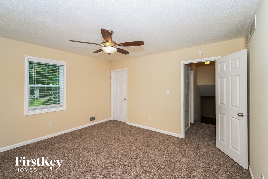 a bedroom with a ceiling fan and a door to a closet